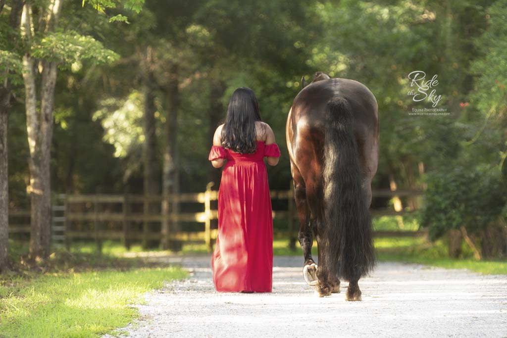 Girl in long red dress walking down path next to horse in Chattanooga, TN