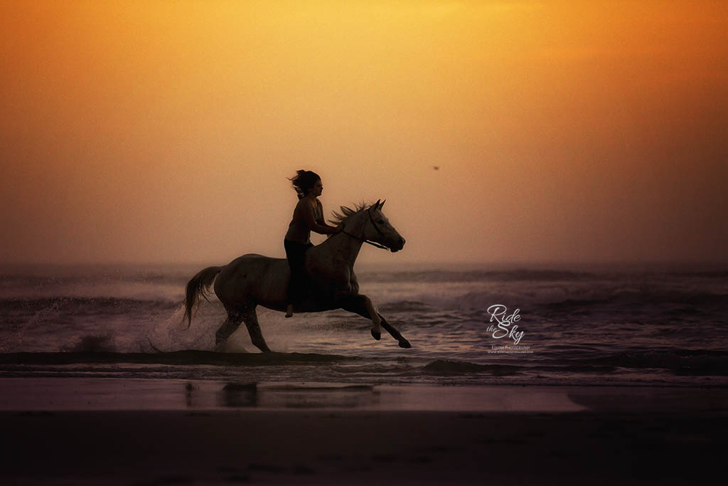 Girl riding horse on beach at sunrise