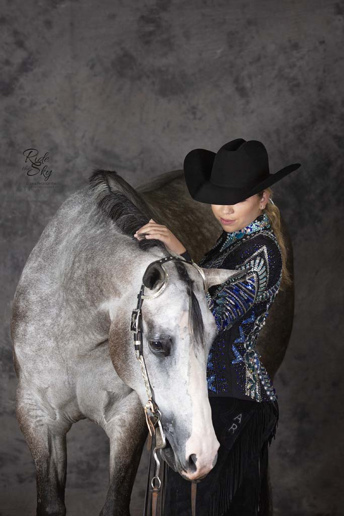 Cowgirl and western show horse in front of backdrop