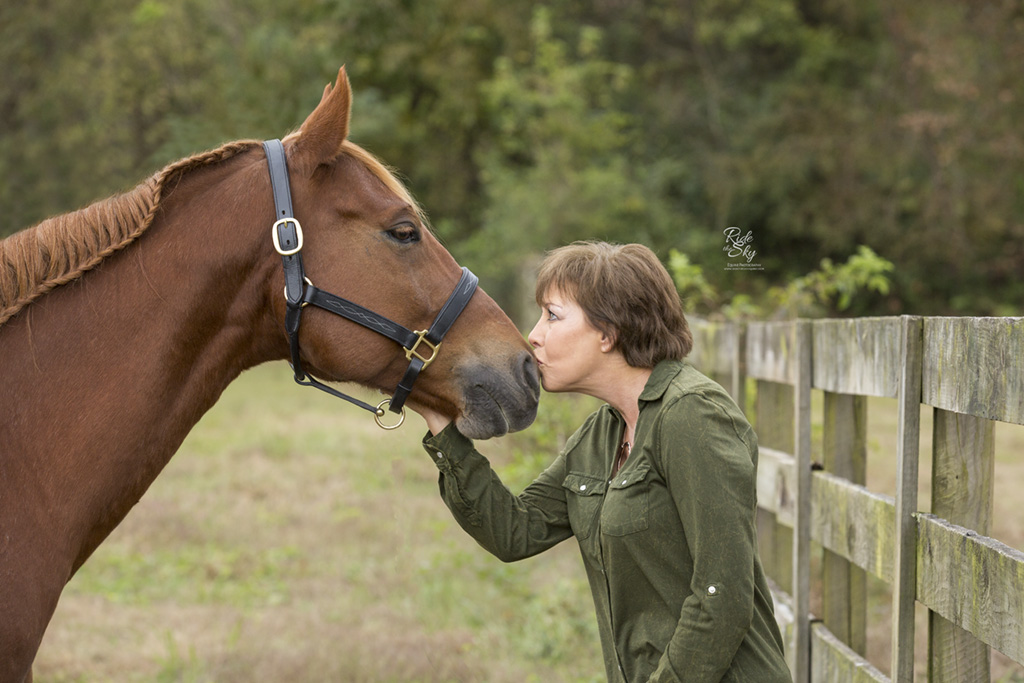 Woman kissing horse muzzle in fall field