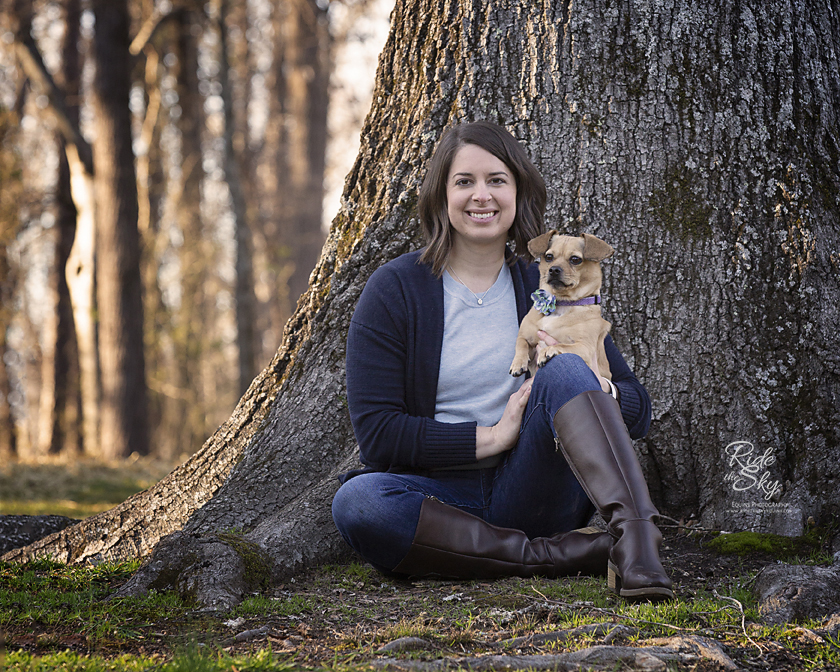 Woman and dog leaning on tree