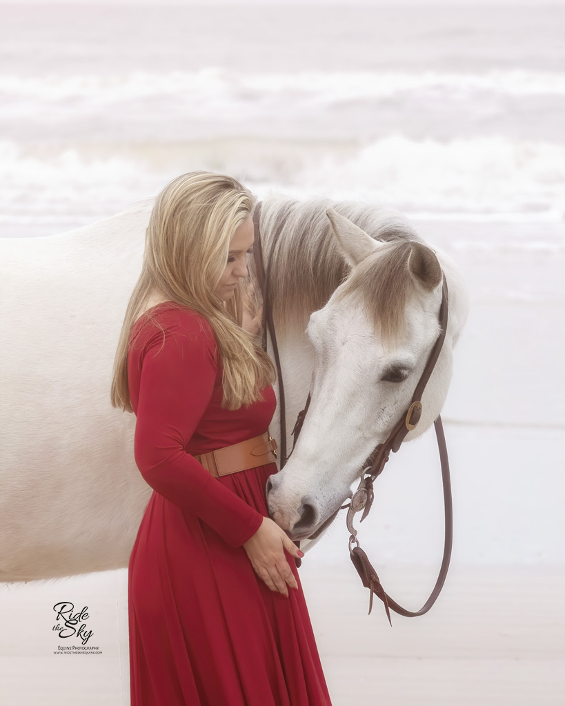 Woman in red dress with horse on beach
