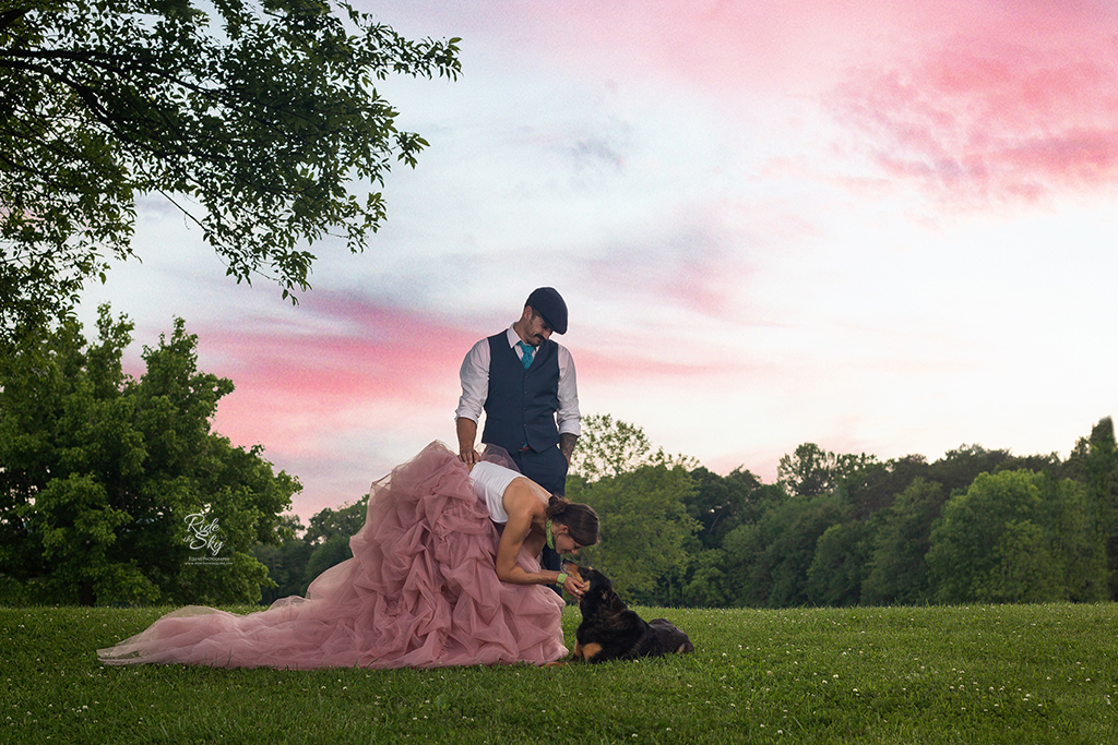 Woman in fancy dress petting dog while man in suit looks on