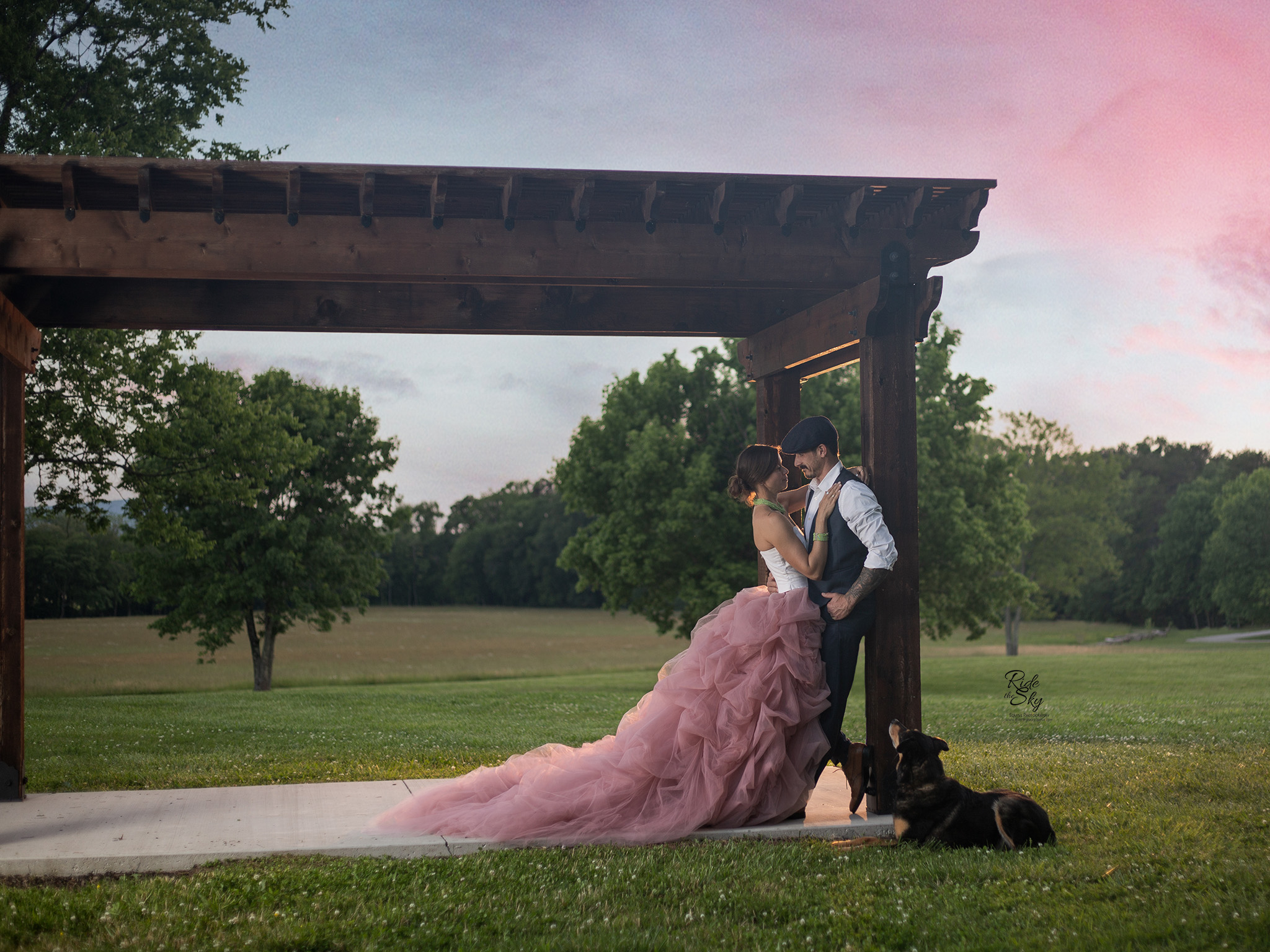 Woman in fancy dress leaning into man in suit who is leaning on pavilion at Kensignton Cove Farm