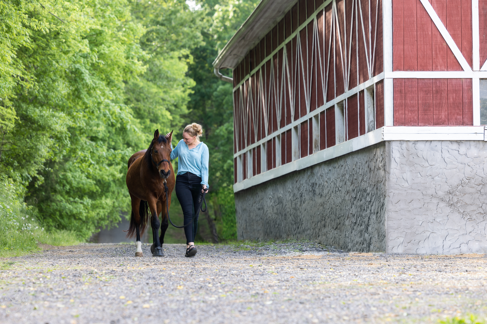 woman and horse walking next to barn