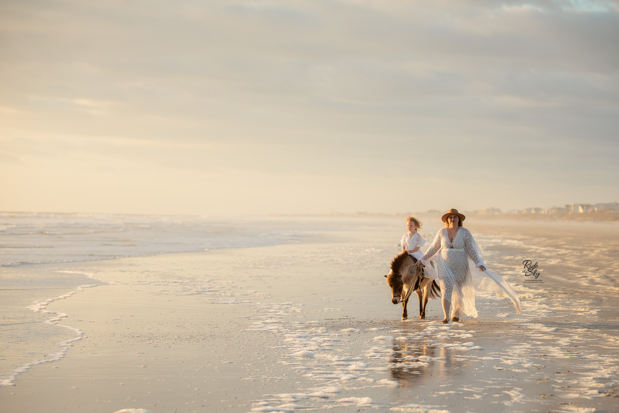 woman and child with mini horse on the beach