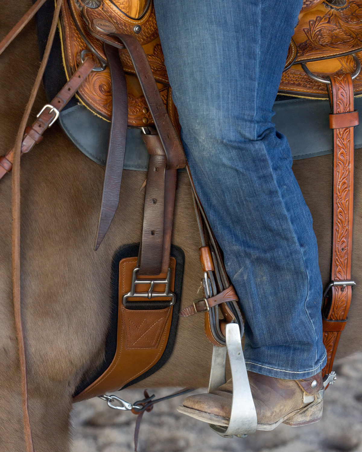 Picture of Total Saddle Fit girth on western saddle with cowgirls leg and stirrup