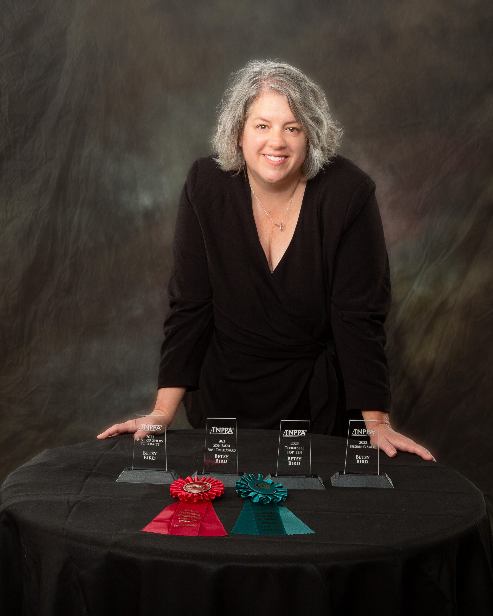 Betsy Bird of Ride the Sky Equine Photography is standing with her photography awards.